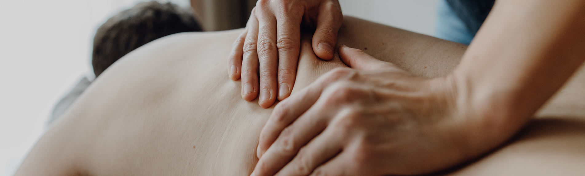 Physiotherapeut massiert Rücken eines Patienten