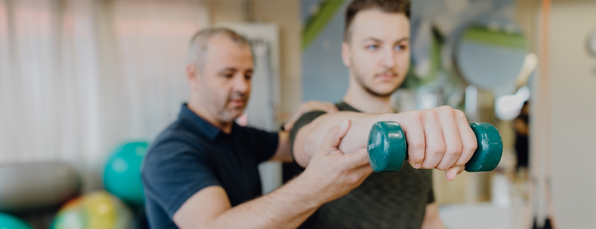 Trainer unterstütze Patient beim Training mit Hantel