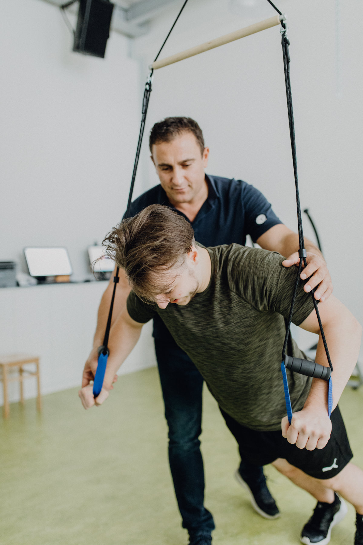 Medizinische Trainingstherapie am Slingtrainer mit Physiotherapeut und Patient